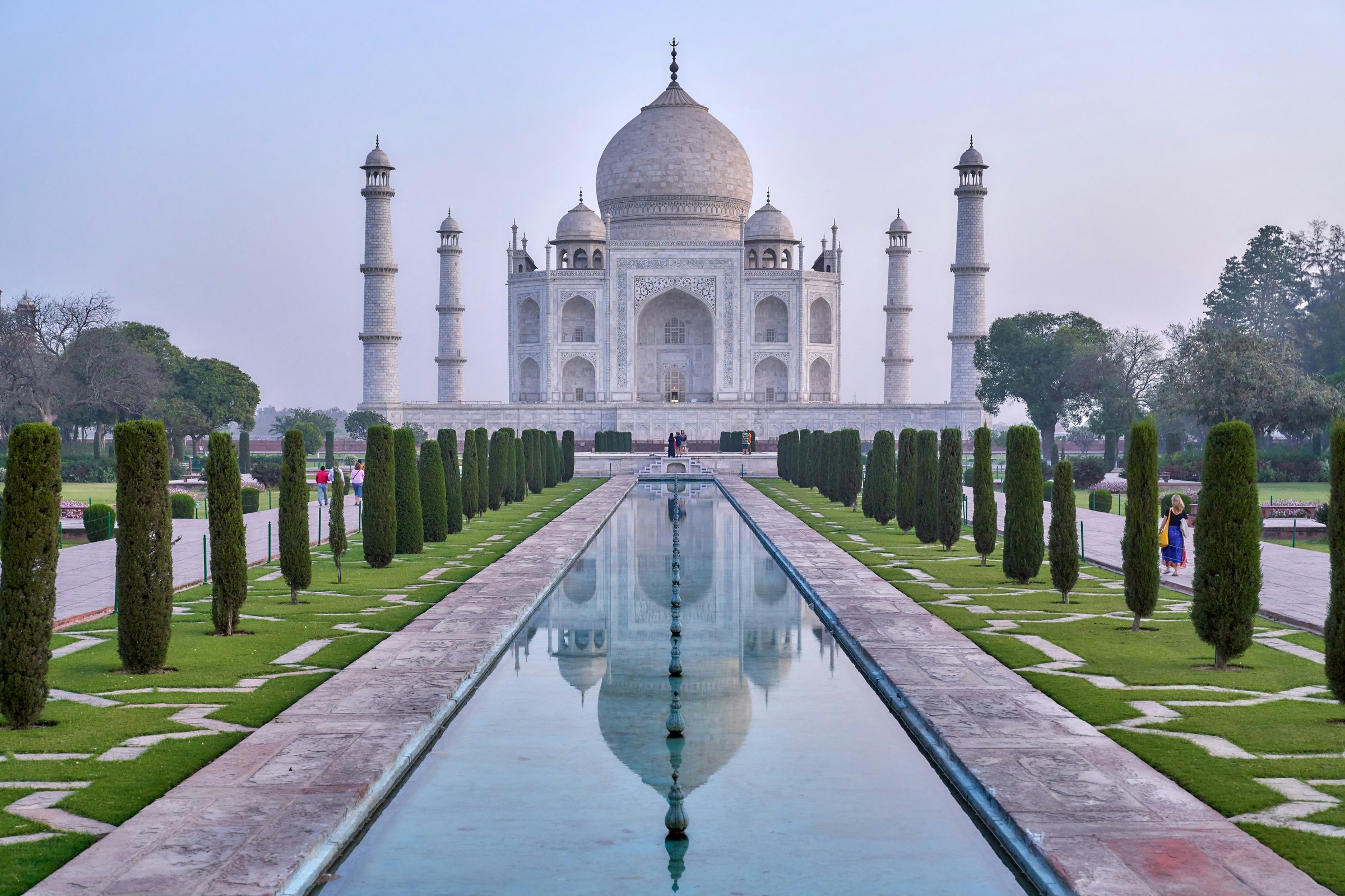 The Taj Mahal reflected in its long pool, framed by symmetrical cypress-lined gardens