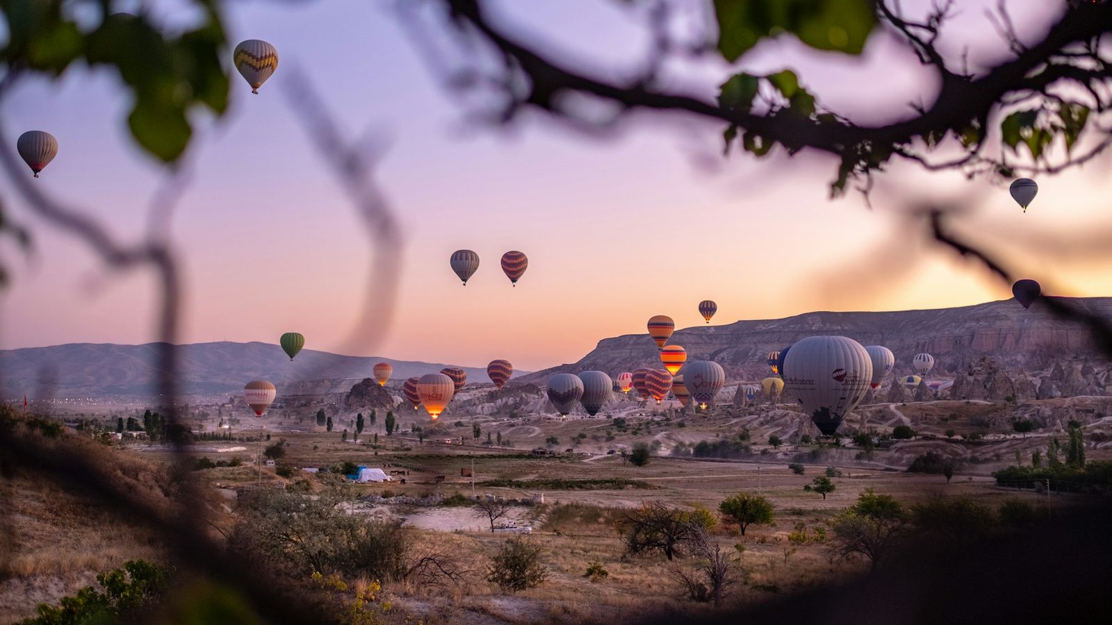 Hot air balloons rising over the valleys of Göreme National Park in Cappadocia, Türkiye, at sunrise