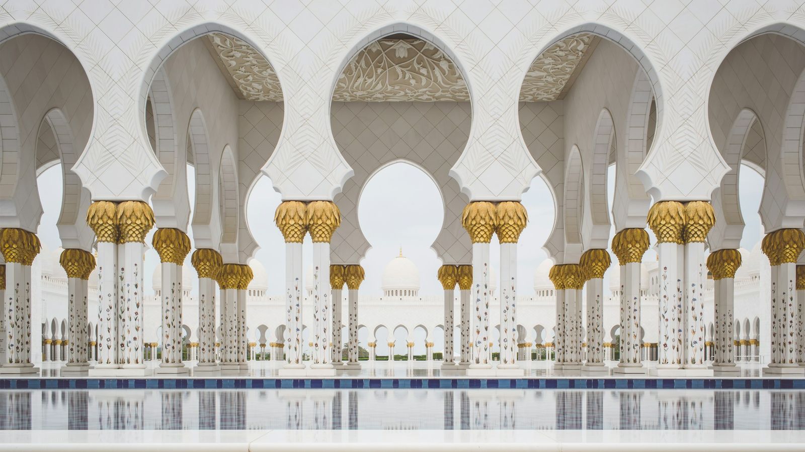 White marble columns of the Sheikh Zayed Grand Mosque in Abu Dhabi reflected in a pool